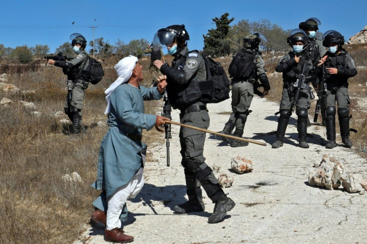 A Palestinian man confronts Israeli security forces after they intervened in scuffles earlier between Jewish settlers and Palestinian farmers in the West Bank