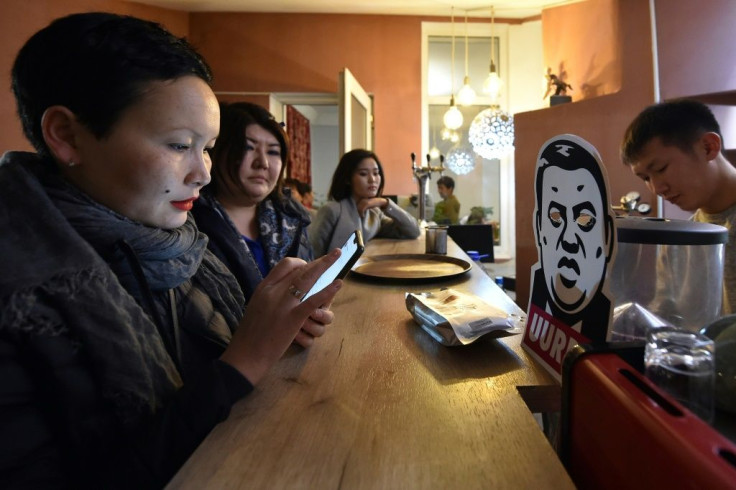 People drink beverages next to a cardboard cut-out depicting Rayimbek Matraimov at an anti-corruption cafe in Bishkek in 2019