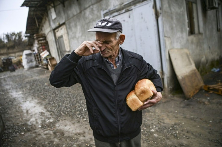 People arrive in cars to pick up bread or carry what they can under their arm