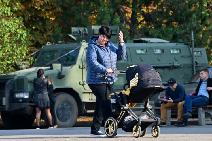 A woman pushes a child in a stroller on the central square in Slovyansk in front of a National Guard vehicle earlier this month