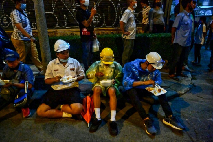 This picture taken on October 21, 2020 shows pro-democracy protesters eating meals from street food vendors during an anti-government rally in Bangkok