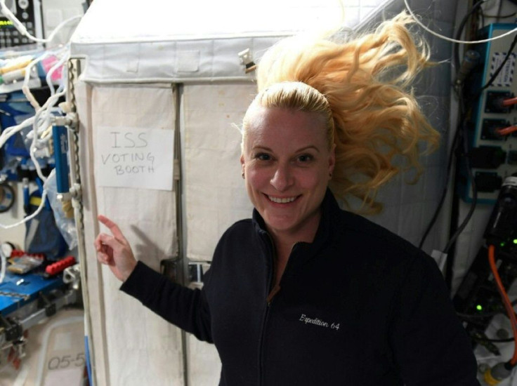 This handout photo released on October 22, 2020 by NASA shows International Space Station crew member Kate Rubins pointing to a sign reading "ISS voting booth"