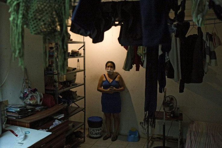 Norelis stands next to a bucket she uses as toilet in the room she where lives with her daughter, at a shelter located in the basement of the Sudameris public building in Caracas