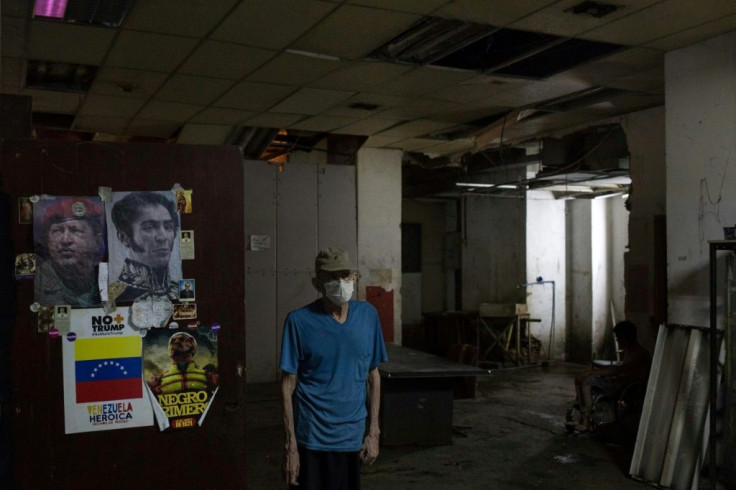 A man stands next to posters depicting Venezuelan liberator Simon Bolivar (R) and late Venezuelan leader Hugo Chavez, at the halls of a shelter located in the basement of the Sudameris public building in Caracas