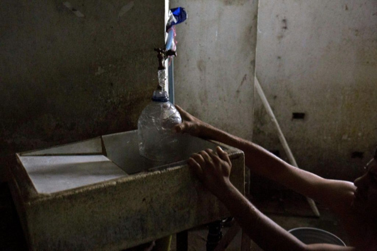 Johan Medina collects water from a pipe at a shelter located in the basement of the Sudameris public building in Caracas