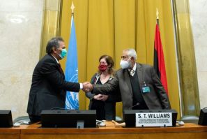 The heads of the rival Libyan delegations shake hands in front of the UN envoy after agreeing to a "permanent" ceasefire