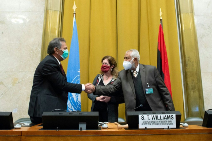 The heads of the rival Libyan delegations shake hands in front of the UN envoy after agreeing to a "permanent" ceasefire