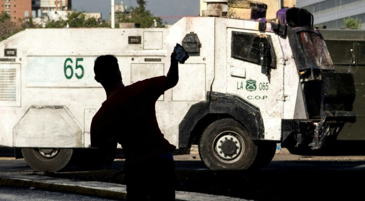 A demonstrator throws a stone against a riot police vehicle during a protest against Chilean President Sebastian Pinera's government in Santiago on October 23, 2020, ahead of Sunday's referendum