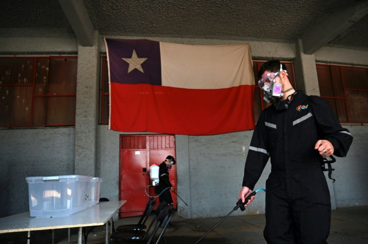 Workers disinfect a polling station in Santiago for Sunday's referendum on changing Chile's Pinochet-era constitution
