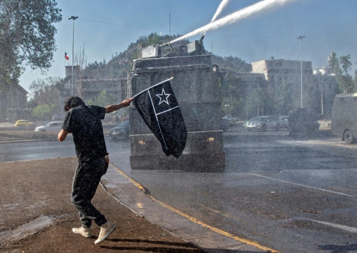 A demonstrator is sprayed by water cannon during a protest against President Sebastian Pinera's government in Santiago ahead of Sunday's referendum