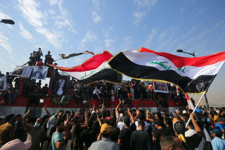 Iraqi demonstrators wave flags as they gather in Tahrir Square in the centre of the capital Baghdad