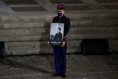 A French Republican Guard holds a portrait of Samuel Paty in Paris on October 21, 2020, during a national homage to the teacher, who was beheaded for showing cartoons of the Prophet Mohamed in his civics class