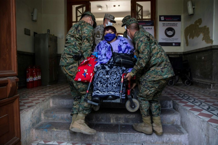 Soldiers carry a woman on a wheelchair at a Santiago polling station during the constitutional referendum vote
