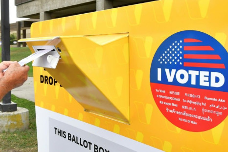 A voter drops a ballot for the 2020 US elections into an official drop box in Norwalk, California