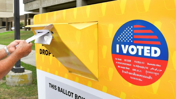 A voter drops a ballot for the 2020 US elections into an official drop box in Norwalk, California