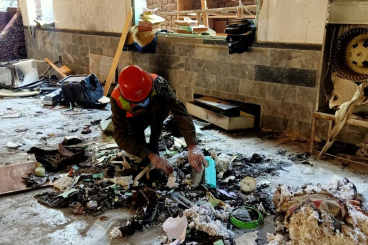 A rescue worker examines the scene of the blast at a religious school in Peshawar