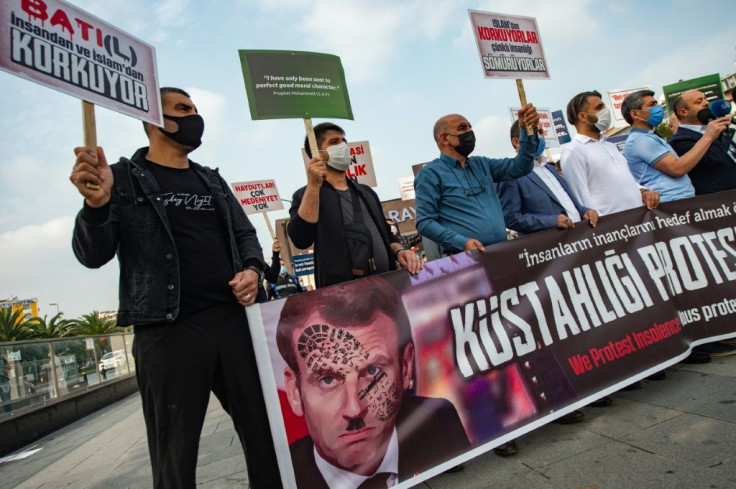 Protesters in Istanbul hold a sign showing French President Emmanuel Macron with a shoe print over his face after he defended the right to mock religion following the beheading of a teacher near Paris who had shown cartoons of the Prophet Mohammed