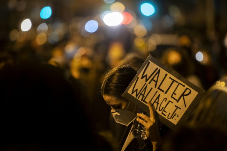A demonstrator, wearing a protective face mask, holds a placard reading "WALTER WALLACE JR." during a protest near the location where Walter Wallace, Jr. was killed by two police officers on October 27, 2020 in Philadelphia, Pennsylvania