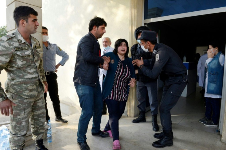 A distraught relative of a person wounded in recent shelling receives support outside a hospital in the town of Barda.