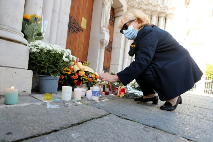 A woman lights a candle outside the Notre-Dame basilica in Nice after Thursday's attack