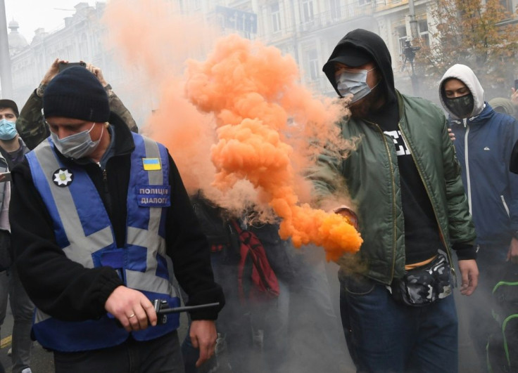 A demonstrator throws a smoke bomb during the protest outside the constitutional court building in Kiev on Friday