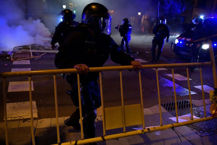 Members of the Catalan regional police force set up crowd control barriers as clashes erupt during a demonstration against new coronavirus restrictions.