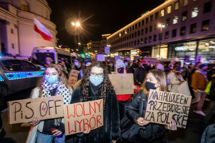 Protesters in Warsaw hold anti-government signs at the mass protest against a court ruling banning almost all abortions in Poland