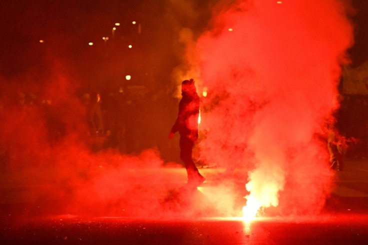 A left-wing activist walks past flares as they take part in a protest rally to demand economic support measures, as the government announced a new series of restrictions to contain the spread of Covid-19 and considers more stringent measures, in Rome