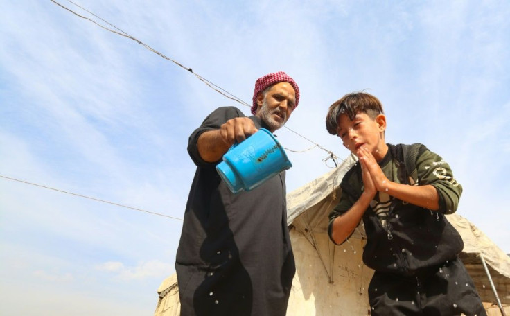 A young boy washes his face in the overcrowded displacement camp