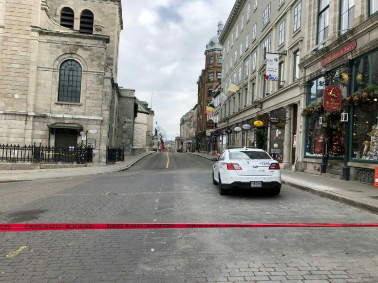 Police cars close off a street in Old Quebecafter a sword-wielding attacker dressed in medieval costume killed two people and injured five others