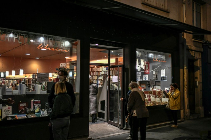People, wearing face masks, queue outside a bookstore to collect books on October 31, 2020 in Paris on the second day of a second national general lockdown decided by the French government to contain the spread of Covid-19 outbreak due to the novel corona