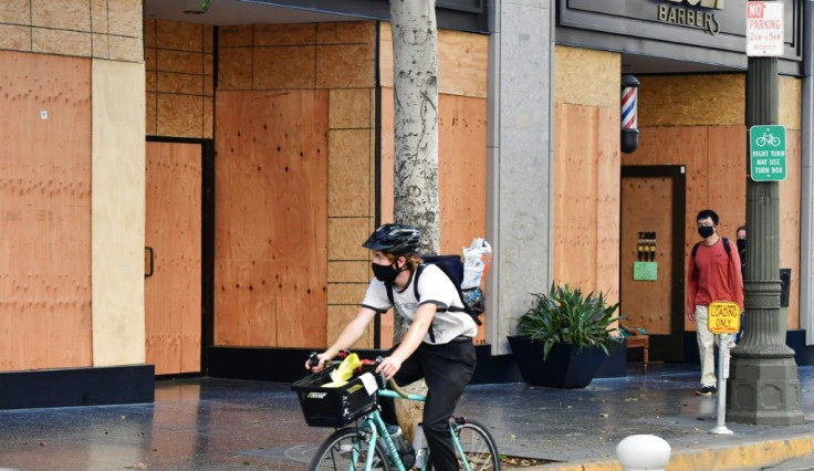 People pass panels of wood used for boarding up businesses, in expectation for potential violence, a day before Election Day on November 2, 2020 in Los Angeles, California