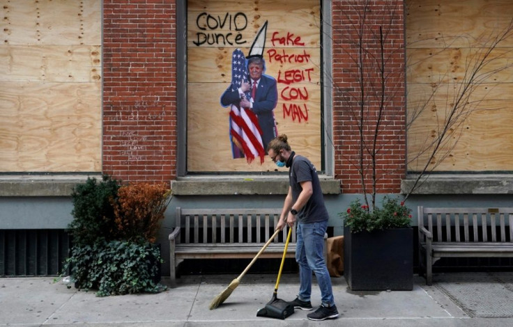 A worker in the Soho area of New York sweeps around businesses boarded up on November 2, with many parts of the country bracing for potential unrest