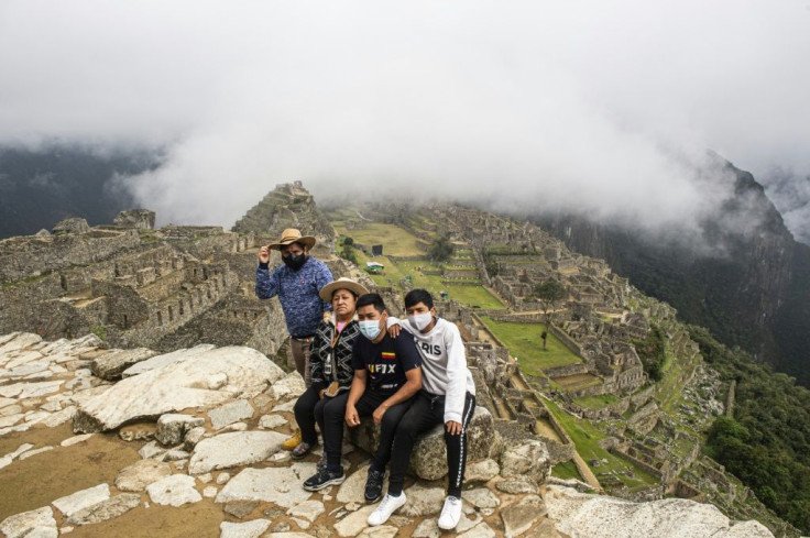 Tourists pose for a photo in front of the archaeological site of Machu Picchu, in Cusco, Peru on November 2, 2020