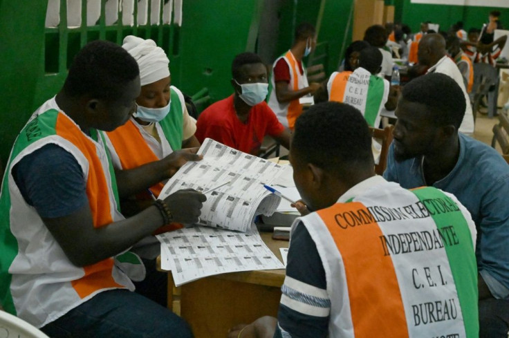 Electoral commission officials check the voter's roll as they count votes at a polling station in Abidjan on October 31, 2020