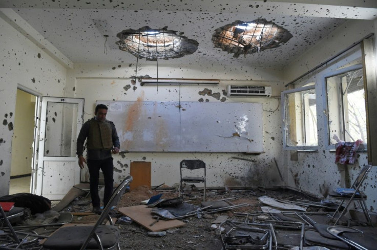 A journalist walks inside a damaged classroom a day after gunmen stormed Kabul university