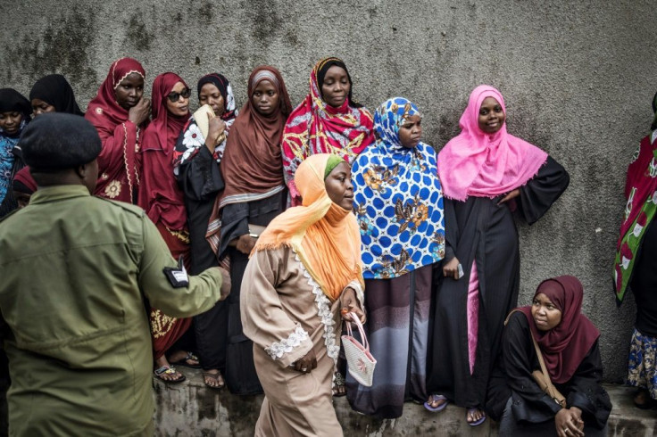 A Tanzanian police officer directs a woman at at a polling station in the outskirts of Stone Town, Zanzibar, on October 28, 2020