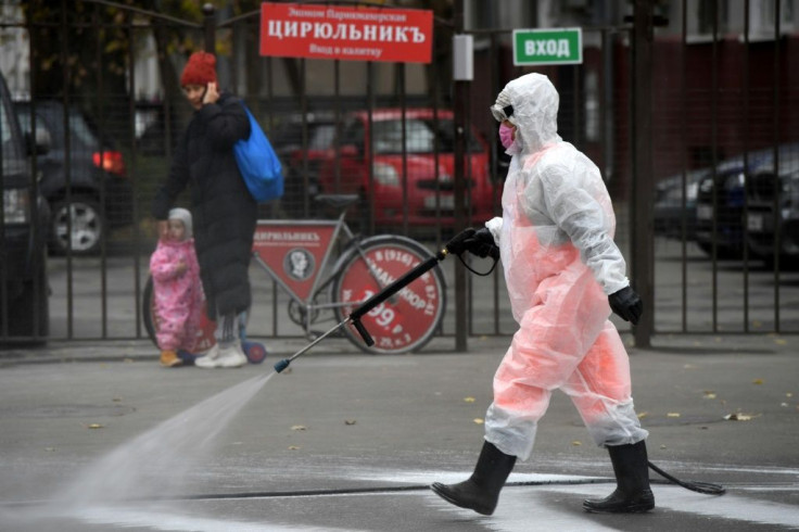 A municipal worker wearing protective equipment sprays disinfectant in Moscow, with Russia announcing a daily record for cases and deaths