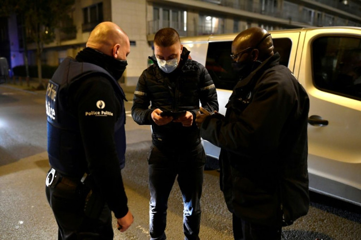 Police officers stop a teenager in Brussels where a curfew is in place