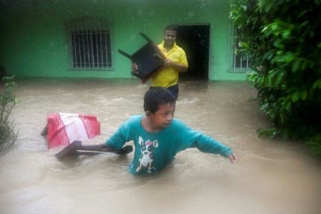 A boy and a man save chairs from a flooded house as heavy rains from tropical depression Eta cause flooding in Izabal, north of Guatemala City in November 2020