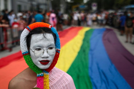 An LGBTQ activist walks past a rainbow banner while taking part in the Pride Parade in Bangkok