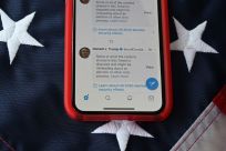 A cell phone displays post from Donald Trump masked with warnings imposed by Twitter, the president's go-to communication tool