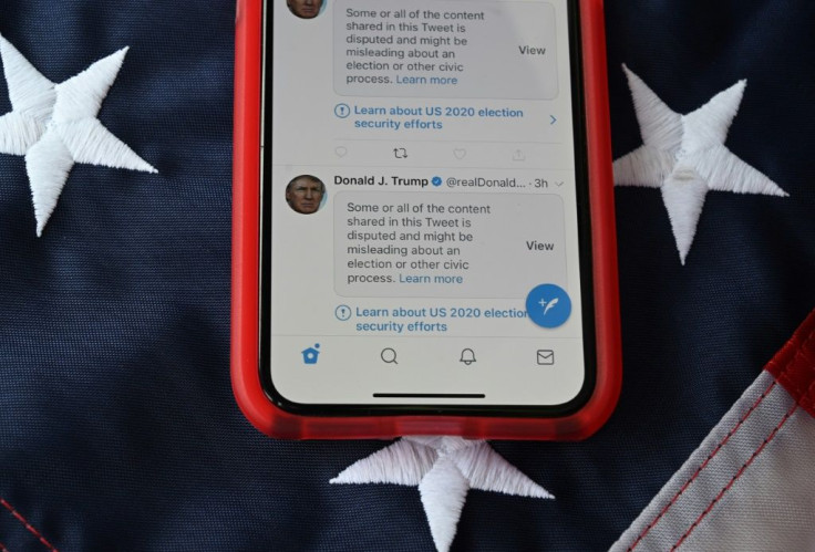 A cell phone displays post from Donald Trump masked with warnings imposed by Twitter, the president's go-to communication tool