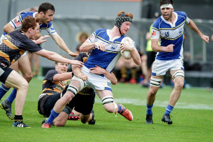 University Squids' George Hitchcock (C) is tackled in the U85kg national final against Eden Lizards in Auckland