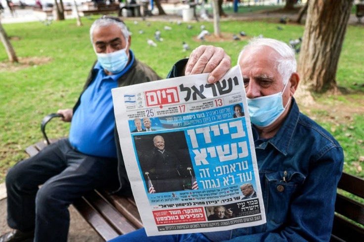 A man holds up a copy of Israeli newspaper Israel Hayom