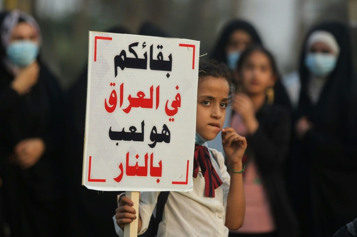 A girl carries a sign reading in Arabic "remaining in Iraq is playing with fire", a message directed at the US military, during a demonstration outside the the Iraqi capital's highly-fortified Green Zone on Saturday