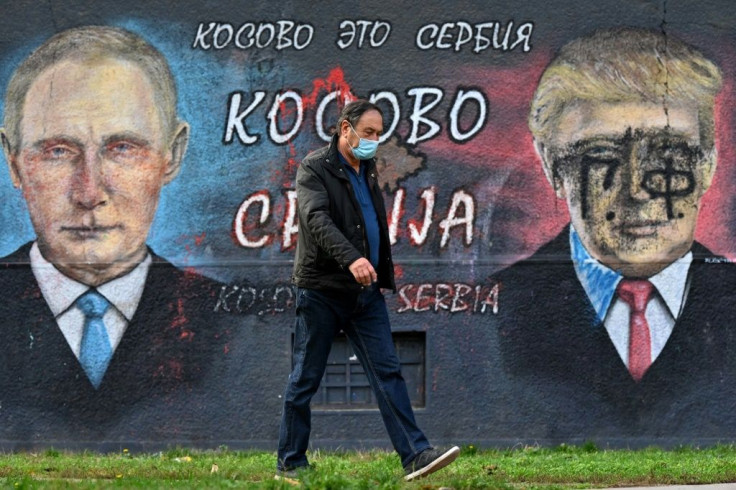 A pedestrian walks past a mural of Russian President Vladimir Putin and US counterpart Donald Trump bearing the words "Kosovo is Serbia"