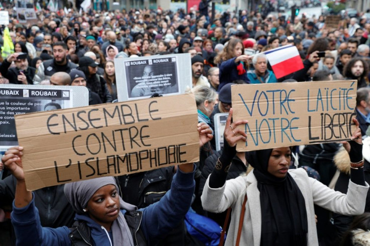 Two women hold placards reading "Together against Islamophobia" (L) and "Your secularism, our freedom" at a Paris protest in 2019