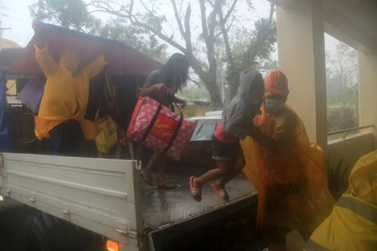 Rescuers help residents from a vehicle during the evacuation in Legazpi City, Albay province