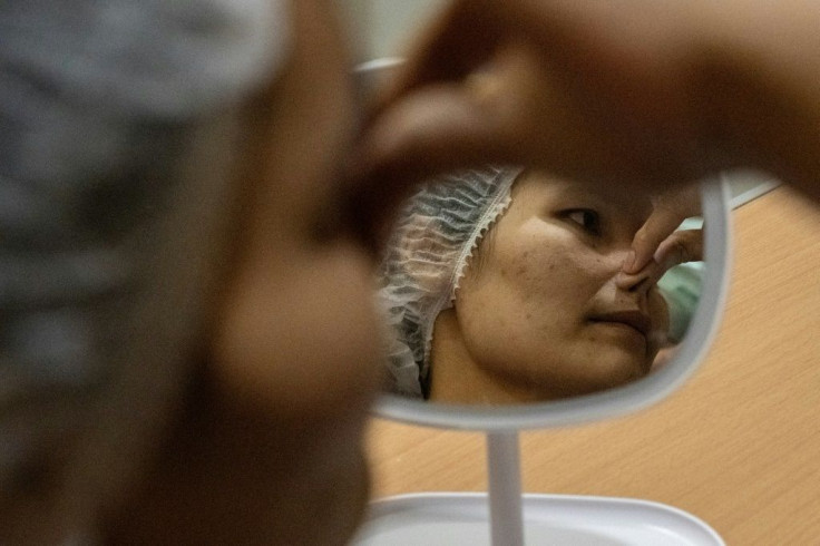 "All my friends called me flat-nose," said Somprasong Aimsantia as she waiting to undergo surgery to install a silicone bridge